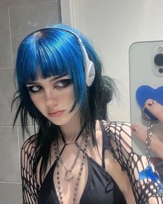 a woman with blue hair and headphones taking a selfie