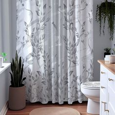 a white toilet sitting next to a bath tub in a bathroom under a window covered in curtains