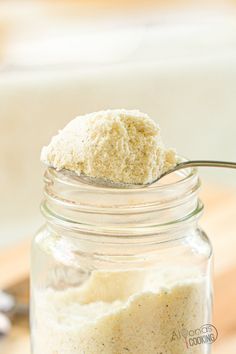 a spoon with some food on it in a glass jar next to a wooden table