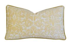 a yellow and white pillow with an ornate design on the front, along with a gold border