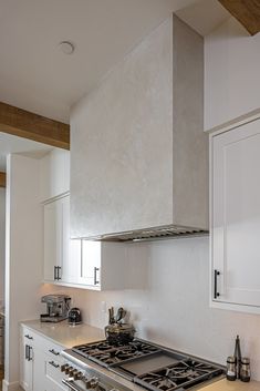 a stove top oven sitting inside of a kitchen next to white cabinets and counter tops