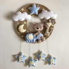 a teddy bear is hanging on the wall next to some stars and a wreath that says baby