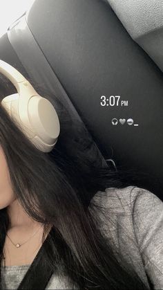 a woman wearing headphones sitting in the back seat of a car with her eyes closed