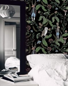 a mirror sitting on top of a bed next to a wallpapered headboard