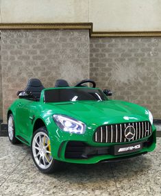 a green mercedes sports car parked in front of a wall with two doors on it