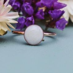 a close up of a ring on a table with flowers and purple flowers in the background