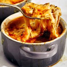 a ladle full of macaroni and cheese being lifted out of a casserole dish