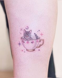 a cat in a cup tattoo on the leg