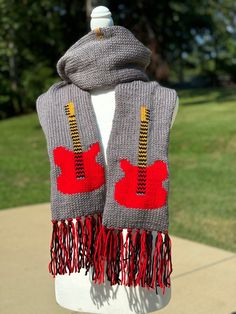 a gray scarf with red and yellow designs on it sitting on top of a white mannequin