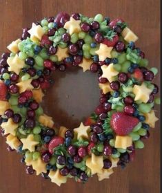 a wreath made out of grapes, strawberries and other fruits is displayed on a table