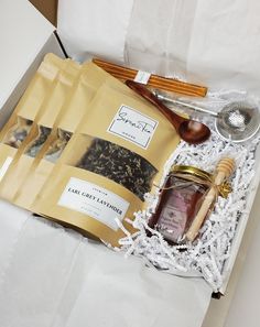 an open box containing various items such as tea, honey and spoons