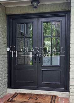 a black double door with two sidelights on the front of a brick building and a welcome mat in front of it