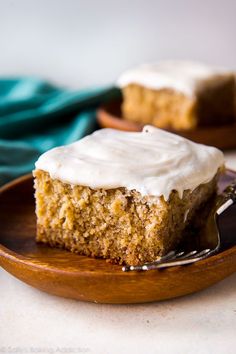 a piece of cake with white frosting on a plate and a fork in the foreground