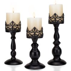 three candles are sitting next to each other on a white surface with black filigrees