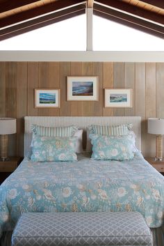 a bedroom with wood paneling and blue bedspread, two pictures on the wall