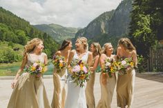 a group of women standing next to each other on a wooden floor in front of mountains