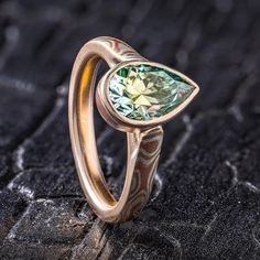 "* Price may vary depending on ring size, please inquire with us directly with your needed size for accurate pricing! This enchanting Mokume Gane ring is shown in the Woodgrain pattern and the Fire metal combination and features a custom made mokume floating bezel setting, holding a stunning green tinted moissanite. The Fire palette features 14k yellow gold , 14k red gold, and sterling silver. Palette: Fire Pattern: Woodgrain Width Shown: 2.5mm Size Shown: 4 Finish: Satin Profile: Low Dome Stone: 9 x 6 x 4.4mm Pear Shaped Moissanite Setting: Floating Mokume Bezel Price does NOT include stones or setting fees, for custom designs like this please inquire with us directly for more detailed pricing! We care about customer service and would like to hear from you! Please contact us to help creat Mokume Gane Rings, Silver Palette, Low Profile Engagement Rings, Mokume Gane Ring, Fire Pattern, Woodgrain Pattern, Mokume Gane, Be Patient With Me, Bezel Ring