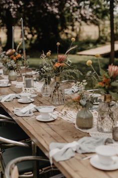 a long wooden table topped with plates and vases filled with flowers