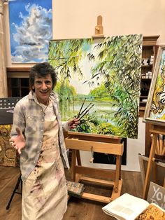 a woman standing next to an easel in front of paintings