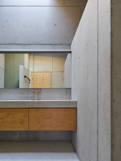 an empty bathroom with concrete walls and counter tops, as seen from the doorway to the other side