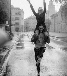 two people running in the rain with their arms up