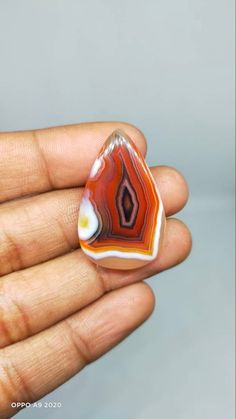 a hand holding a red and white glass object in it's left palm area