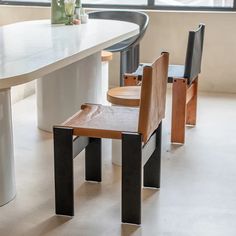 two wooden chairs sitting next to each other on top of a white table in front of a window