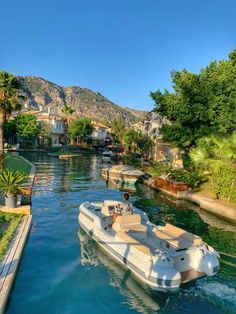 a boat traveling down a river next to a lush green hillside covered with palm trees