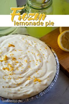 a frozen lemonade pie is sitting on a cutting board next to sliced lemons