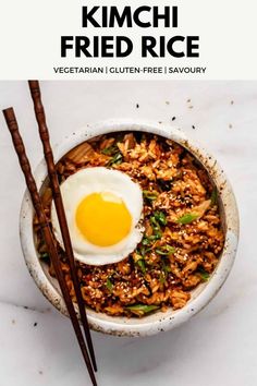 an overhead view of a bowl of food with chopsticks and an egg on top