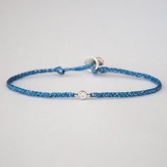 "Diamond friendship bracelets Sparkly Blue These beautiful charm bracelets are made to be treasured. A perfect white diamond is bezeled in 14k solid gold and then hand braided with a water-resistant sparkly blue nylon cord. Your perfect stacking bracelet. They make great affordable fine jewelry gifts. Your bracelet will be sent to you in our black Vivien Frank gift box. Details: White diamond 0.06 cts. 14k solid gold bezel Sterling silver clasp color: Sparkly Blue If you have any questions about Braided Friendship Bracelet, Diamond Friendship Bracelet, Rose Gold Beaded Bracelet, Braided Friendship Bracelets, Affordable Fine Jewelry, Tube Bracelet, Silk Bracelet, Bracelet Quotes, Rose Gold Beads