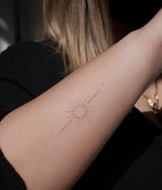 a woman's arm with a tattoo on it that has a sunburst in the middle