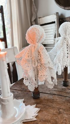 two white crocheted angel figurines sitting on top of a wooden table