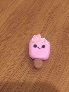 a pink donut with sprinkles on it sitting on top of a wooden table