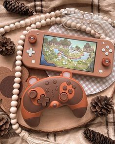 a nintendo wii game controller sitting on top of a wooden table next to pine cones