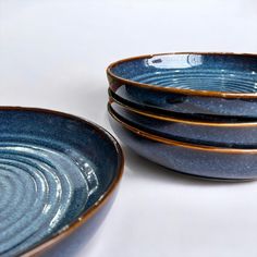 three blue bowls with gold rims stacked on top of each other in front of a white background