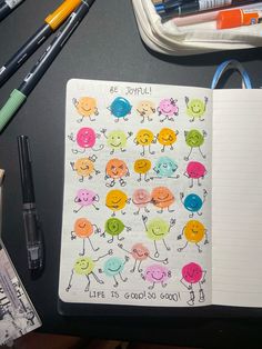 an open notebook with colorful stickers on it next to some pens and pencils