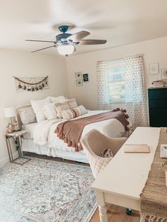 a bedroom with a bed, desk and ceiling fan