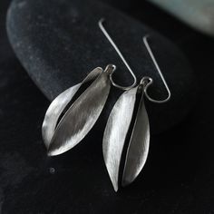 These earrings were created from a single sheet of silver, etched on the surface and folded into the shape of a Thai flower called Champak (Michelia Champaca) which is commonly featured in Thai flower garlands. Traditional Thai ladies can sometimes be seen wearing a champak flower behind their ear, or a handful of the flowers can be found floating in a bowl of water as a home-scenting accessory. The flower is simply hanging from the sterling silver hook and although it is not soldered, it doesn' Handmade Silver Earrings, Jewellery Maker, Silver Silk, Flower Handmade, Handmade Sellers, Team Board, Silver Earrings Handmade, Loop Earrings, Fashion Group