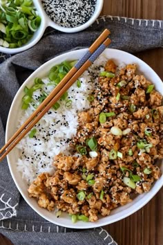 a white bowl filled with rice and meat next to chopsticks