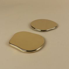 two shiny metal plates sitting on top of a white countertop next to each other