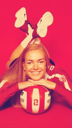 a woman laying on the ground with a volleyball ball in front of her and two legs behind her