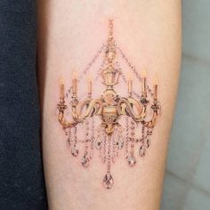 a woman's arm with a chandelier tattoo on it