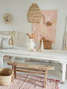 a white table topped with a wooden bench next to a basket and potted plant