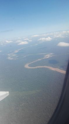 an airplane wing flying over the ocean and land