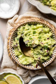 a bowl full of guacamole with a spoon in it next to other bowls