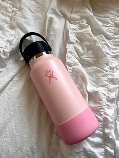 a pink and black water bottle laying on top of a white sheet with the lid up