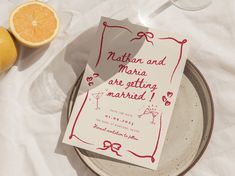 a couple of oranges sitting on top of a plate next to a paper with the words nathan and mary are getting married