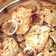 a pan filled with chicken and mushrooms on top of a wooden table next to a knife