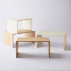 three different tables and one bench made out of plywood, with white walls in the background